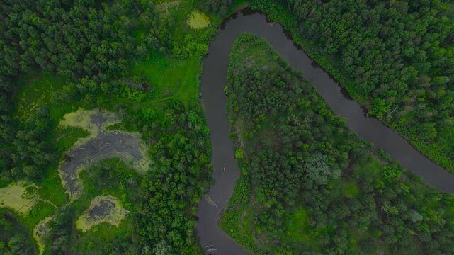 A cinematic high-altitude drone aerial shot starting with a top-down view of a winding river and smoothly tilting up to reveal a remote small village in the distant horizon of Altai Krai.