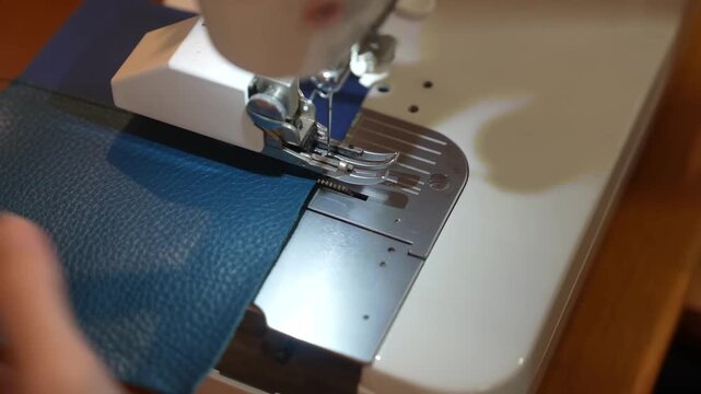 Sewing machine stitches edge of textured blue leather panel