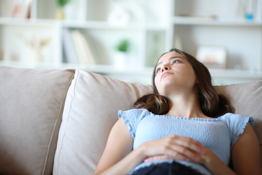 Serious pensive teenage girl on a couch looking away