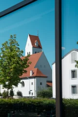 Reflection of Evangelical Lutheran Erloeserkirche church in large modern glass window in Fuerstenfeldbruck, Bavaria, mix of historic Protestant architecture and contemporary building facade in Germany © Natalia Schuchardt