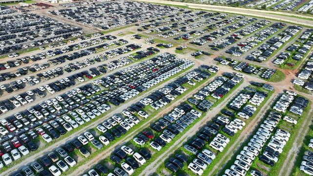 Aerial view of massive car stockpiles awaiting distribution, reflecting market oversupply, changing consumer demand, inventory management, and long-term automotive industry transformation. 4k.
