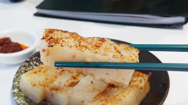 Cantonese Pan Fried Turnip Radish Cake Lifted by Chopsticks Close-Up