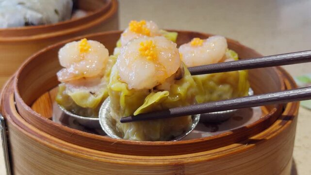 Cantonese Shrimp Shumai Dim Sum Lifted by Chopsticks in Bamboo Steamer
