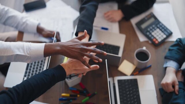 Collaboration of coworkers for success in business, partners folding hands. Multiethnic colleagues unite together, closeup view in office, teamwork and partnership, corporate culture in business