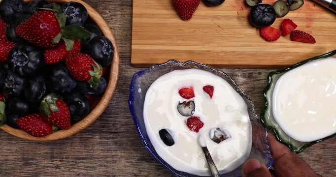 Fruity Strawberry blueberry in wooden bowl Greek style yogurt in glass bowl chopping board knife shopped slice fruit on rustic wooden background Fruit yogurt focus mix move drop keep