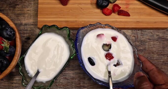 Fruity Strawberry blueberry in wooden bowl Greek style yogurt in glass bowl chopping board knife shopped slice fruit on rustic wooden background Fruit yogurt focus mix move drop keep