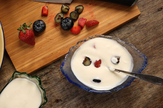 Fruity Strawberry blueberry in wooden bowl Greek style yogurt in glass bowl chopping board knife shopped slice fruit on rustic wooden background Fruit yogurt
