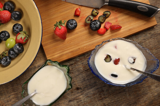 Fruity Strawberry blueberry in wooden bowl Greek style yogurt in glass bowl chopping board knife shopped slice fruit on rustic wooden background Fruit yogurt