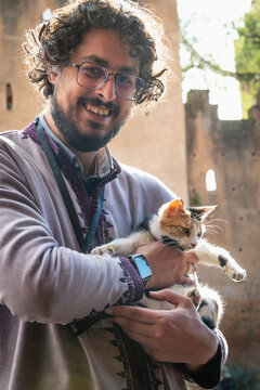 Friendly bearded man holds a small calico cat in Chefchaouen