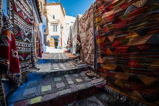 Colorful woven carpets hanging in a blue city alley