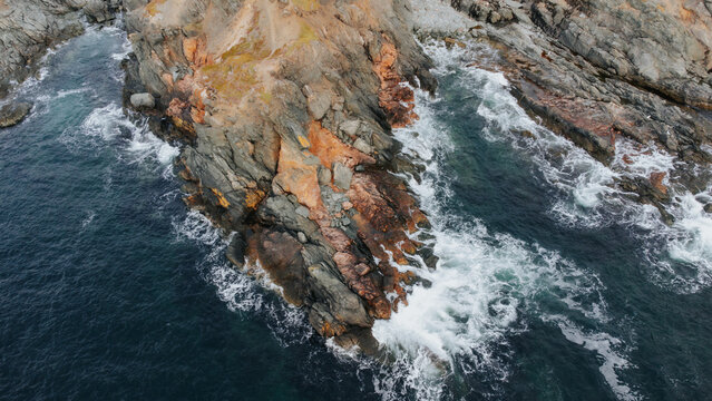 Waves crashing on a craggy headland from above