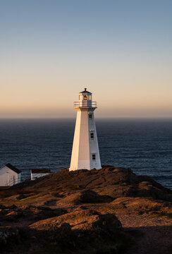 White lighthouse on a rocky coast in warm evening light