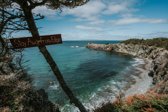 Handmade warning sign overlooking a rocky ocean cove