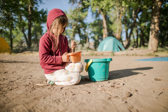 Child plays with bucket and sand on camping trip