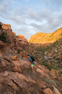 Adventurous hiker scrambles up a red rock slope