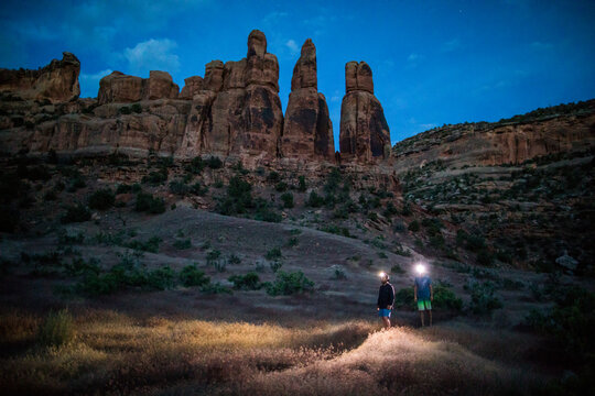 Two hikers with headlamps explore a desert canyon