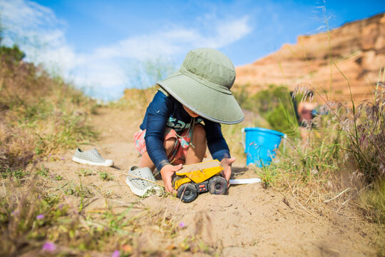Toddler boy playing with toy dump truck in the sand