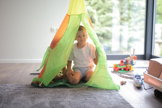 Little boy sitting inside a colorful play tent