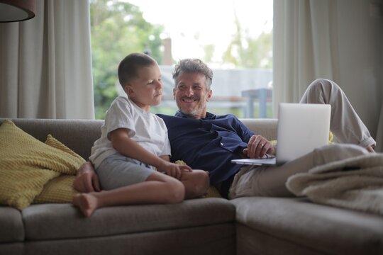 Happy father and son talking on the couch at home