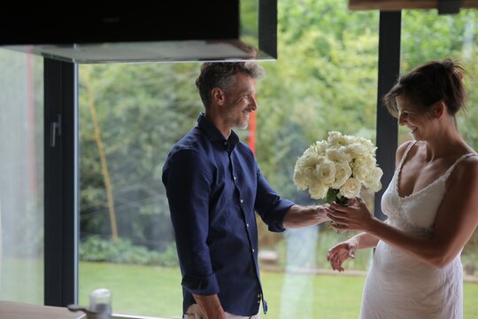 Man giving smiling woman a bouquet of white roses