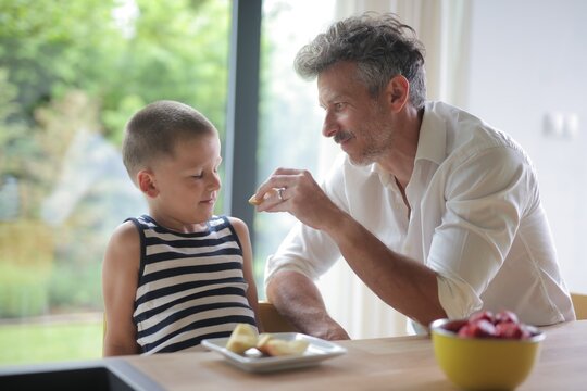 Caring father feeds his son an apple slice