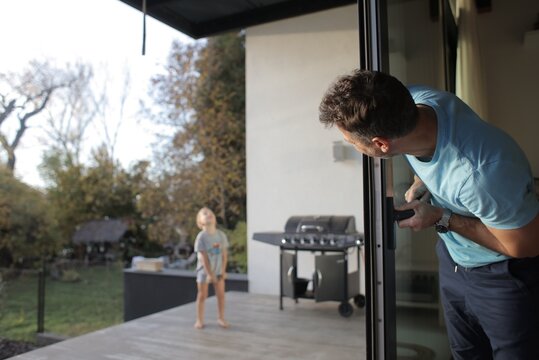 Father peeking out sliding glass door at child