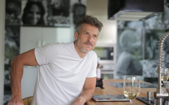 Handsome middle aged man looking thoughtful in kitchen