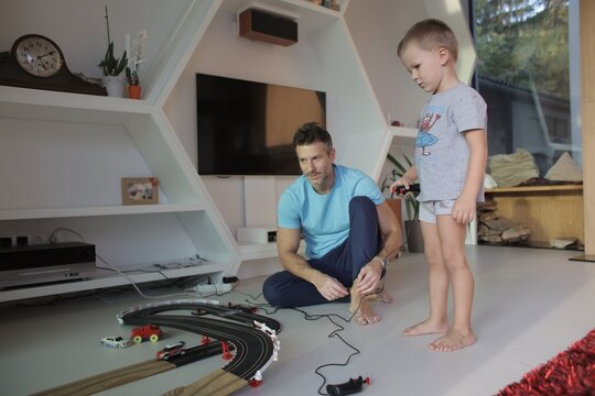Father and son playing with a toy race track at home