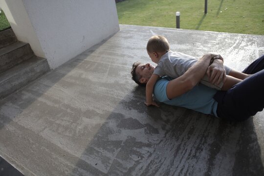 Father and son playfully wrestling on the ground