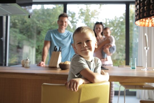 Cute boy smiles at camera with family behind