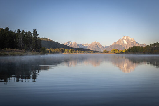 Calm Mountain Lake With Misty Reflection and Forested Shoreline