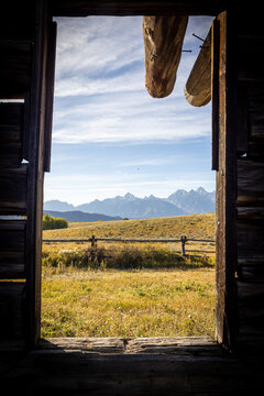 Mountain View Through Old Log Cabin Window Framed by Meadow and