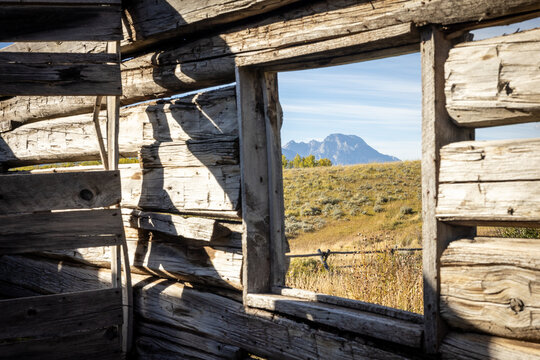 Mountain View Through Old Log Cabin Window Framed by Meadow and