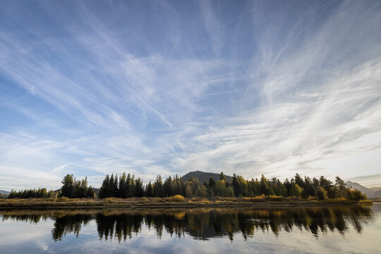Autumn Lake Shoreline With Tree Reflections Under Wispy Blue Sky