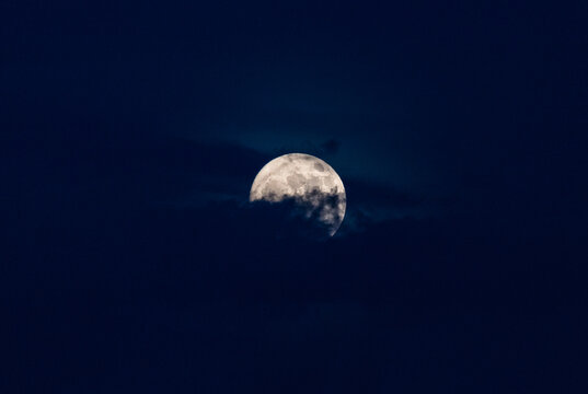 Bright full moon shining through dramatic clouds in the night sky