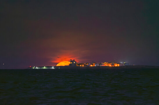 Stunning giant orange full moon setting behind Tabarca Island