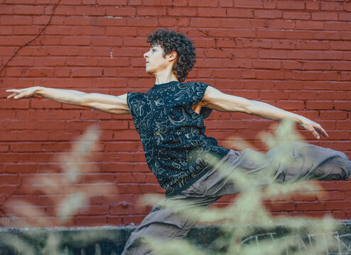 Graceful young person dancing against a brick wall