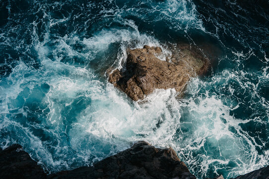 Turbulent blue ocean waves crash on rocky shore in Madeira
