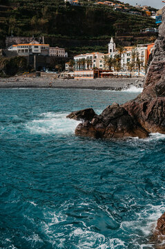 Coastal village view from the ocean with rocky shore - Ponta do Sol