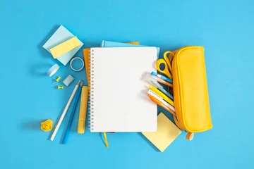 Bright Back to School Flat Lay with Open Blank White Notebook and Yellow Pencil Case on Light Blue Background. Colorful Office and Education Stationery Supplies Top View Composition. © prime1001