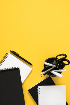 Vertical Flat Lay with Notebooks, Pen, and Stationery Organizer on Bright Yellow Background. Contrast Minimalist Office and Back to School Concept with Ample Copyspace on Top. Top View