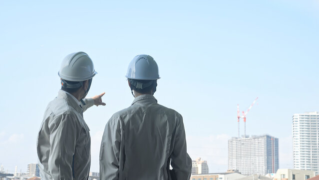 建設中の都市を眺める男性作業員のグループ。工事、チームワーク、安全、点検、建築、現場、ビルメン、検査
