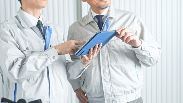 打ち合わせする男性作業員のグループ。建設、工事、工場、業者、相談、会議、DX、修理、点検、建築、内装