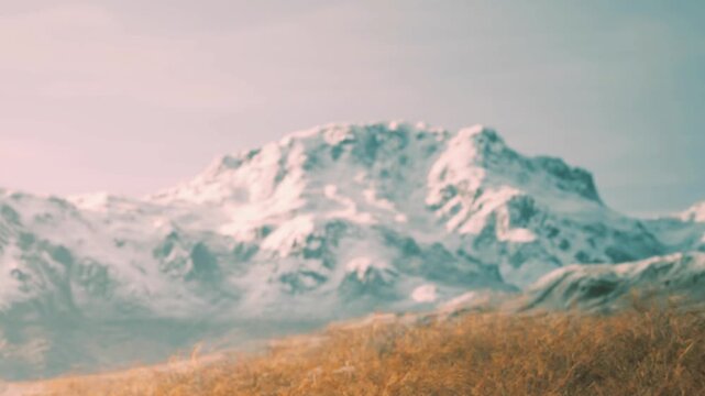 Snow covered mountains rise in the distance with a grassy area in the foreground. The sky appears bright and clear, suggesting a sunny day in a natural setting.