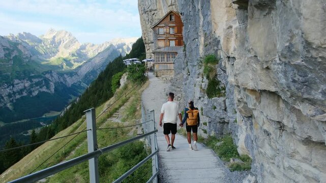 Switzerland unveils breathtaking landscapes as two hikers traverse the scenic paths of Ascher Ebenalps. Majestic mountains rise above, inviting travelers to embrace the beauty of nature.