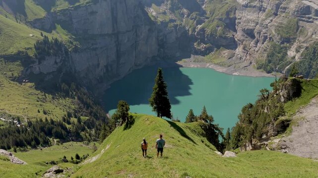 Oeschinensee Switzerland captivates with breathtaking views of turquoise waters surrounded by majestic mountains. A couple of men and women hiking in the Swiss Alps in summer