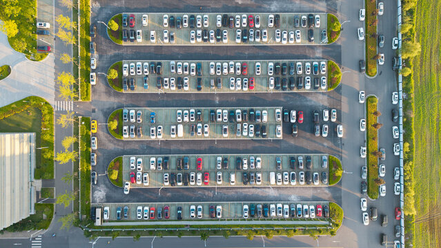 Top-down aerial view of neat landscaped outdoor parking lot full of cars