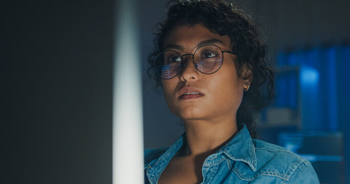 Close-up Black female programmer with code reflection in glasses working late in home office at night. Cybersecurity, AI algorithm, Network security, software developer, serious face, burnout concept.