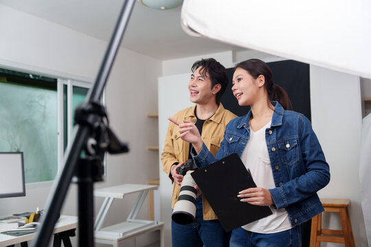 Asian creative directors planning photoshoot with camera and clipboard in studio