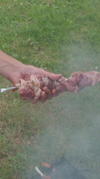 Person preparing marinated meat skewers for grilling